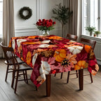 A rectangular dining table covered with a vibrant autumn floral tablecloth featuring pumpkins, leaves, and red roses, surrounded by four wooden chairs in a bright dining room.