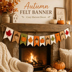 Autumn felt banner garland with hanging fabric flags featuring maple leaves, acorns, pumpkins, and leaves in warm fall colors, displayed across a rustic fireplace in a cozy fall-decor setting.